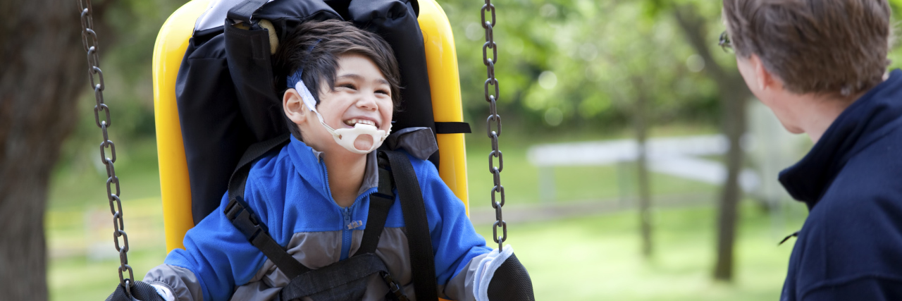 Child with a disability at a park using an accessible swing