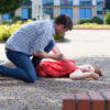 Man trying to help unconscious woman on the street.