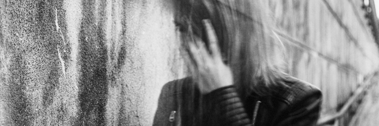 black and white photo of woman in leather jacket walking outside. she appears confused and disoriented.