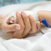 Mother holding baby's hand covered with gauze to keep IV in place