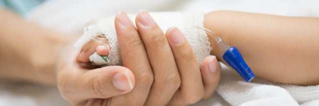 Mother holding baby's hand covered with gauze to keep IV in place