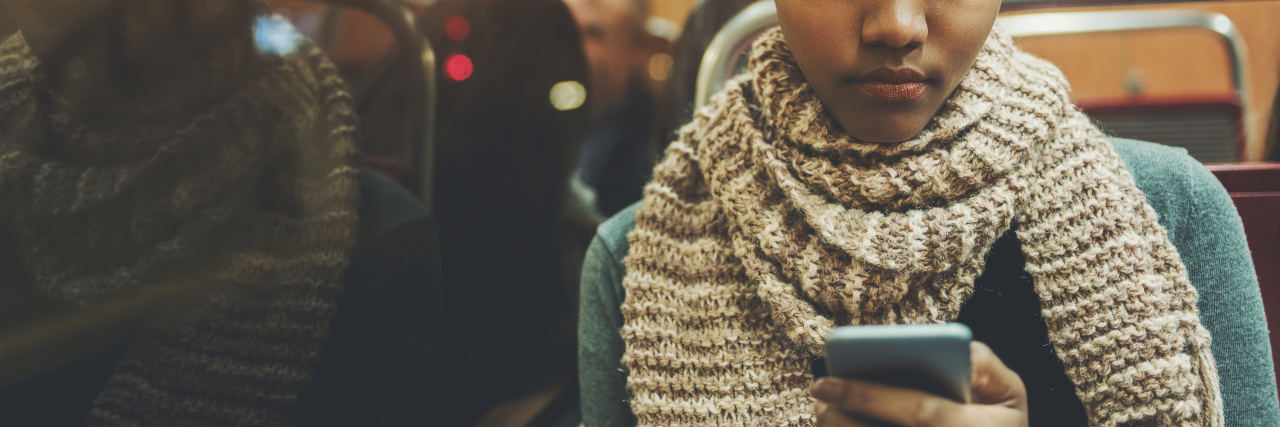 woman reading text message on phone while sitting on bus or train