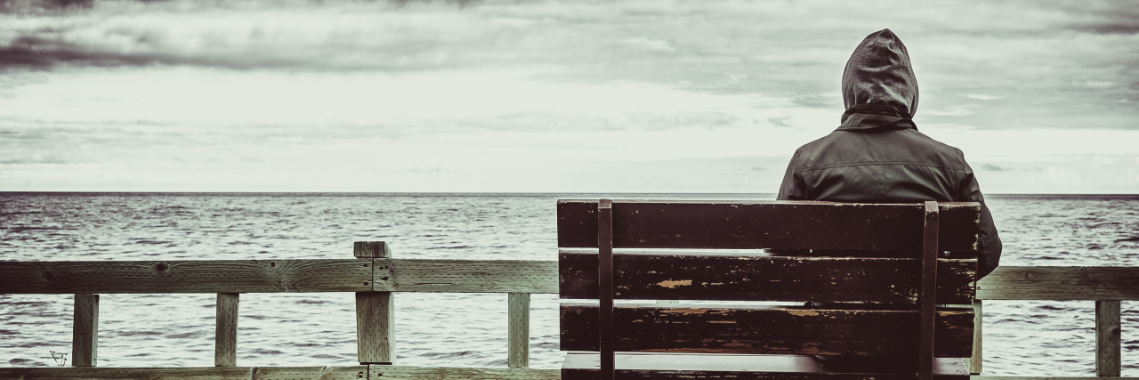 Emotional Impact of Living With Churg-Strauss Vasculitis Man sitting on bench overlooking sea