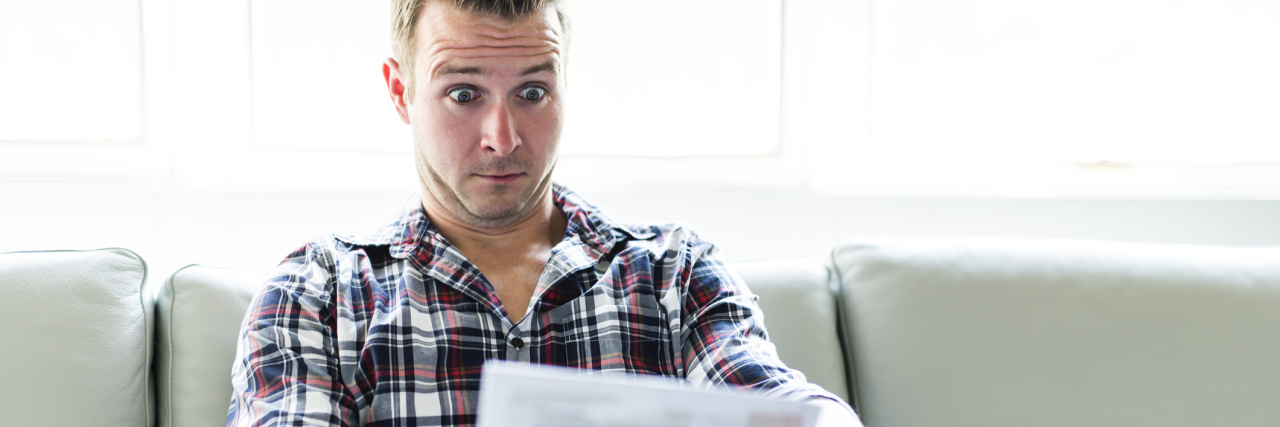 KHN: Sens. Release Bipartisan Plan to Lower Health Costs A Shocked man holding some documents in the livingroom