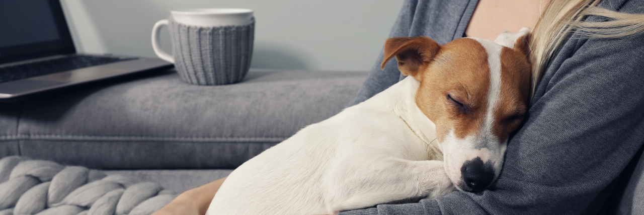 The Differences Between a Service Dog and a Pet Woman sitting on couch holding her dog.