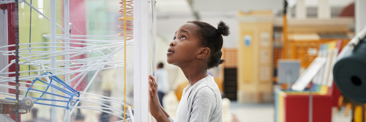 Young black girl looking at a science exhibit.