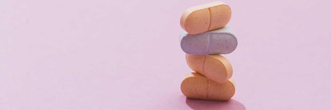 stack of pill and capsule with shadow on pink background