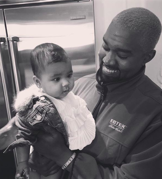 Black and white image of Kanye West holding his daughter
