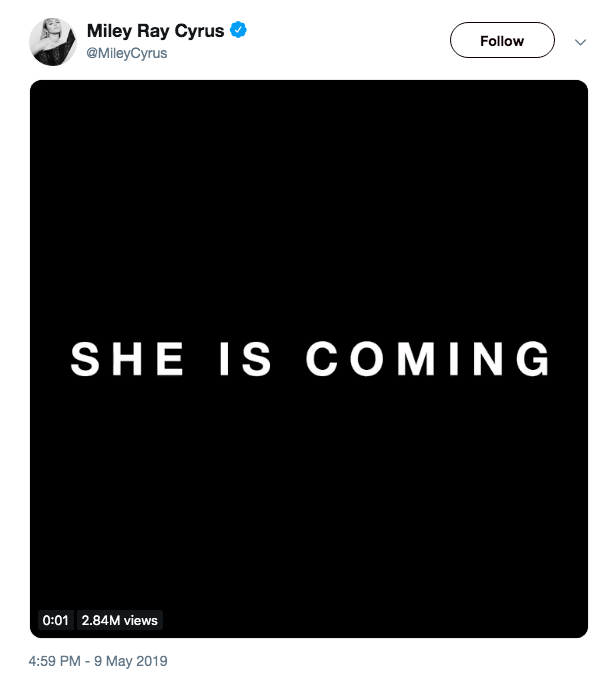 tweet from Miley Cyrus that features a flashing black and white graphic with the words 'she is coming'