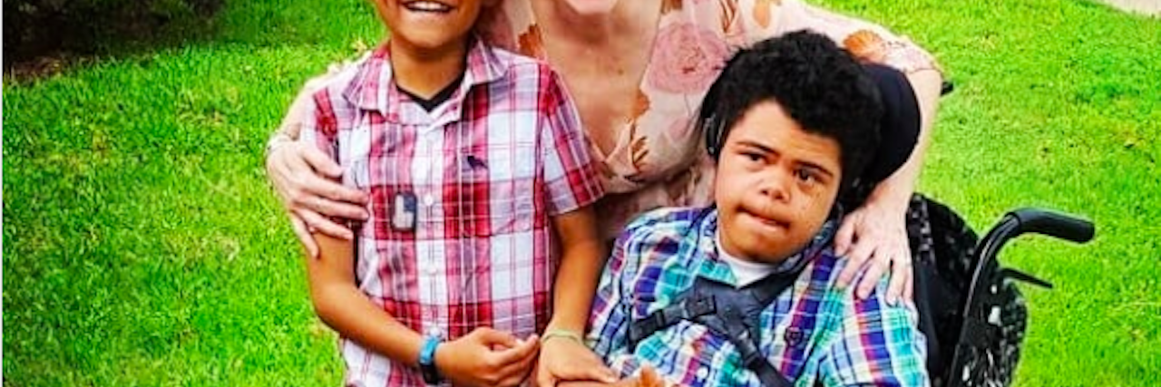 When Kids Ask About My Son With Disabilities, 'What's Wrong With Him' Mother hugging two children, one is sitting on a wheelchair.