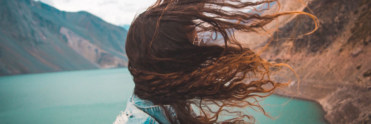 Bipolar Disorder: What 'Stability' Feels Like A woman with her hair blowing in the wind, standing in front of a body of water