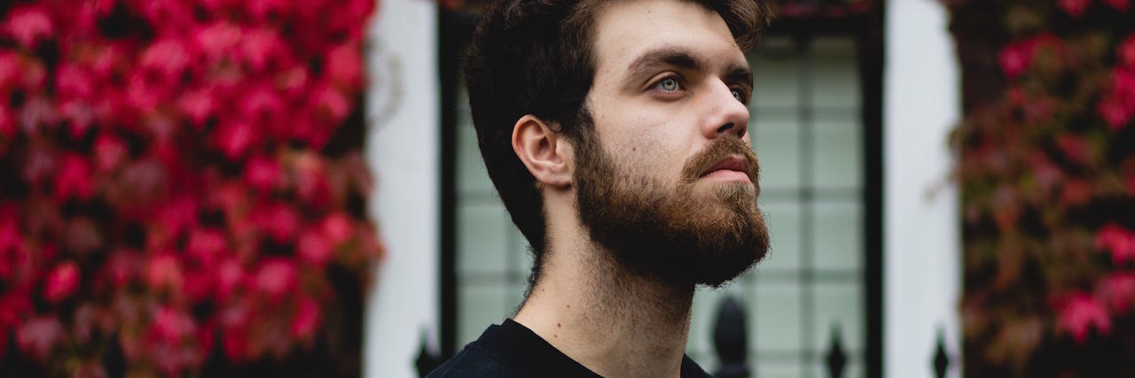 What It's Like to Get OCD Treatment at a Hospital A man looking up, standing in front of a building covered with flowers