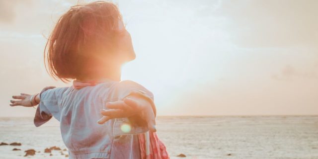 Relaxation Techniques You Need to Try for Chronic Tension and Chronic Pain photo of woman at sunrise or sunset with arms outstretched behind her in relaxation or happiness