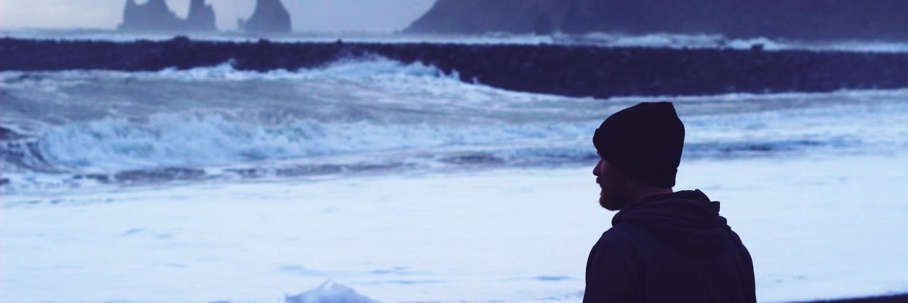 The Difference Between My Medical Trauma and 'Classic' PTSD photo of man looking out to rough ocean and rocky coast