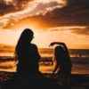 photo of mother and daughter silhouetted against sunset on beach in front of ocean