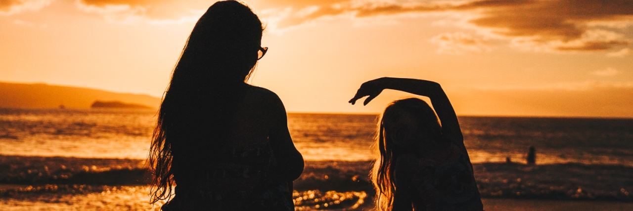 How to Help Young Girls Develop Positive Body Image photo of mother and daughter silhouetted against sunset on beach in front of ocean