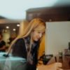 woman with long blonde hair writing in a coffee shop