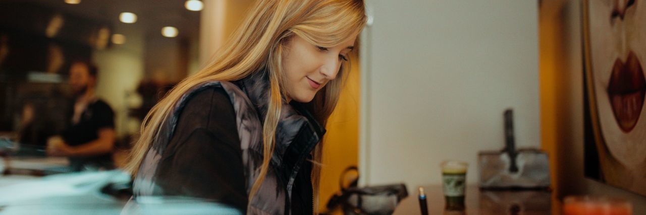 What to Know If You've Just Been Diagnosed With Lyme Disease woman with long blonde hair writing in a coffee shop