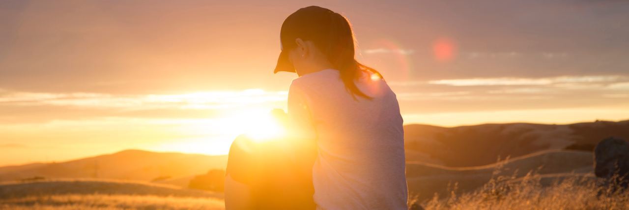 photo of young woman at sunset facing away and silhouetted by sun