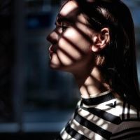 photo of woman with dark hair partly silhouetted by light through window