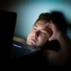 photo of man unable to sleep at night with laptop balanced on chest