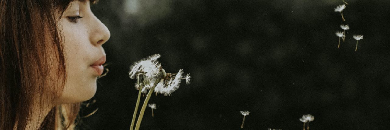 A Simple Metaphor for Eating Disorder Recovery close up photo of young woman blowing dandelion seeds