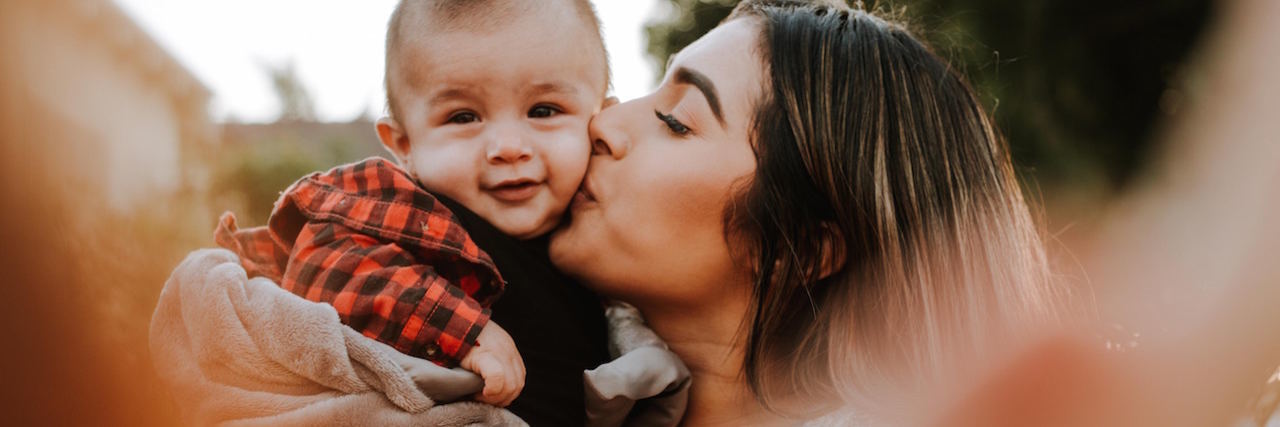 Advice for Mothers With Bipolar Disorder Who Are Struggling A woman and her baby. She's kissing her baby's cheek.