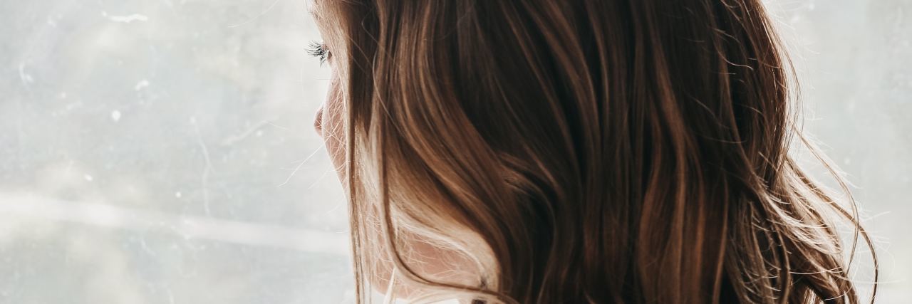 photo of woman looking out of window with long, wavy hair