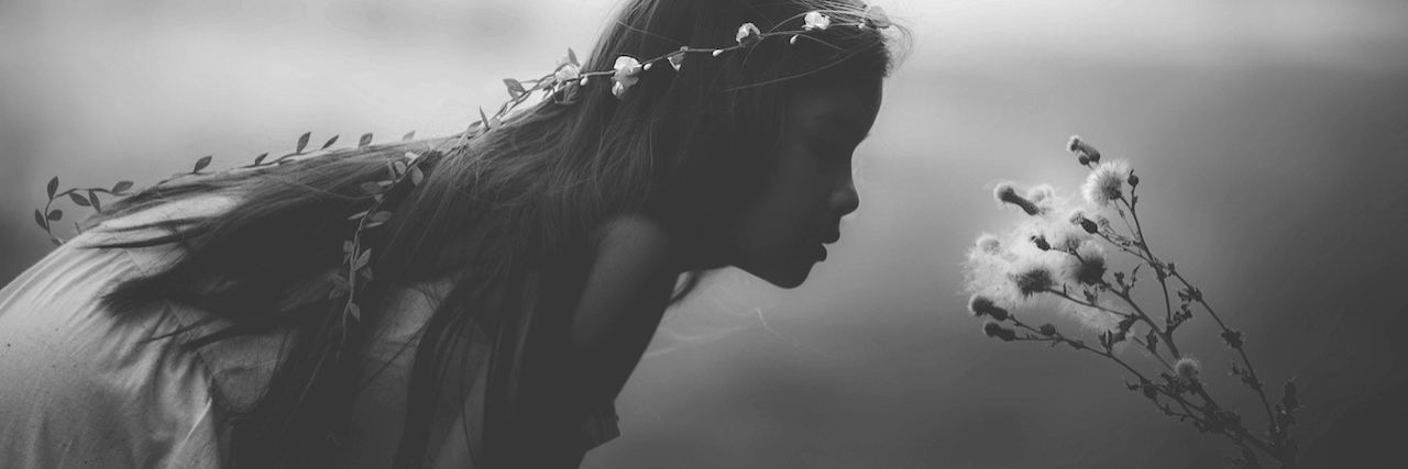 What Young Girls With Anxiety Should Know A young girl wearing a flower crown leaning over the smell a flower