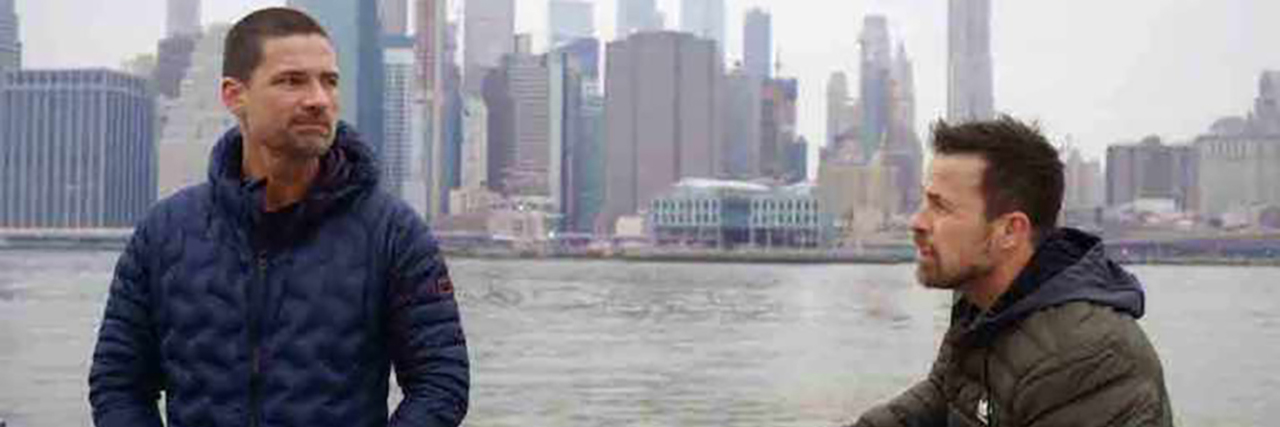 The Village TV Show Features Physical and Mental Health Disabilities Warren Christie and Kurt Yaeger talking on The Village in front of the Hudson River with New York City's skyline in the background.