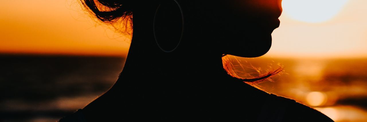 How to Get Through the Summer When You Don't Love Your Body silhouetted photo of woman in summer against sunlight and sea