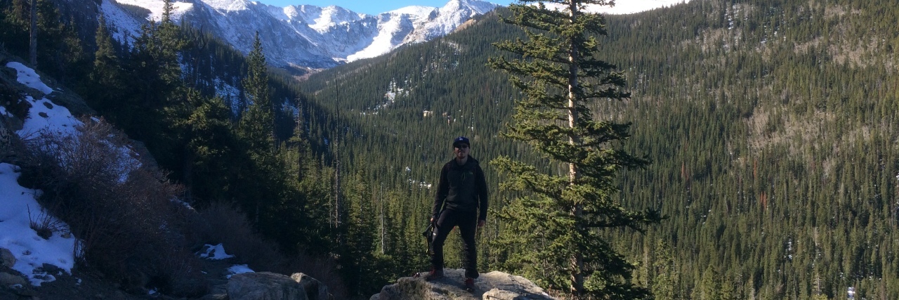 Read This If You're Worried About Telling Someone You're Suicidal photo of man posing in mountains with pine forest and mountains behind him.