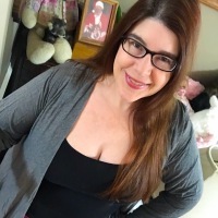 A woman with glasses is smiling at the camera.