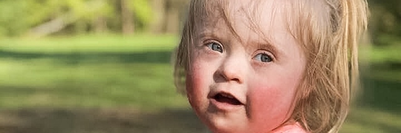 Little girl with Down syndrome playing in sandpit