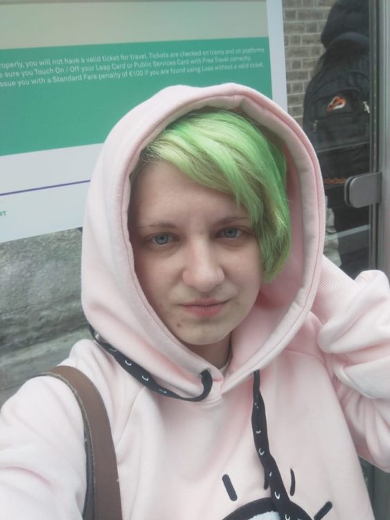 woman in pink hoodie with bright green hair