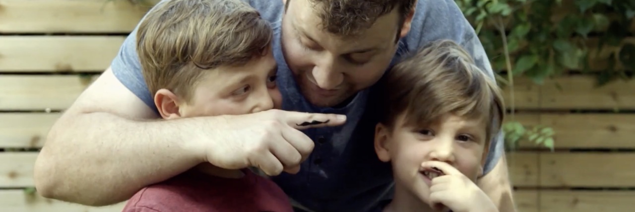 photo of Adam Anava with two sons and with moustaches painted on their fingers