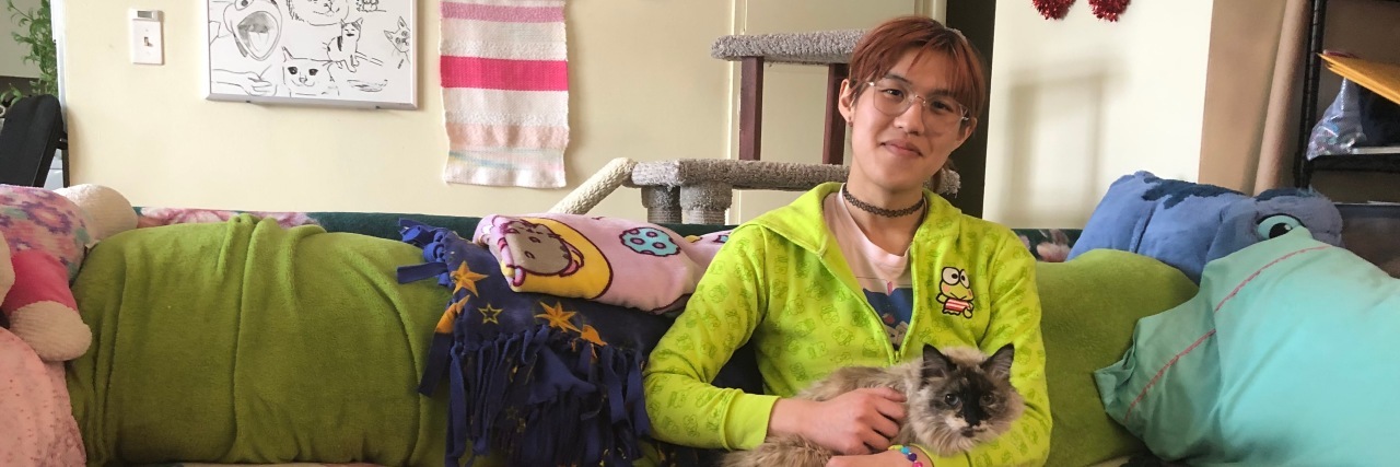 Chronic Illness and Disability in the LGBTQ Community Angel sitting on a green couch.