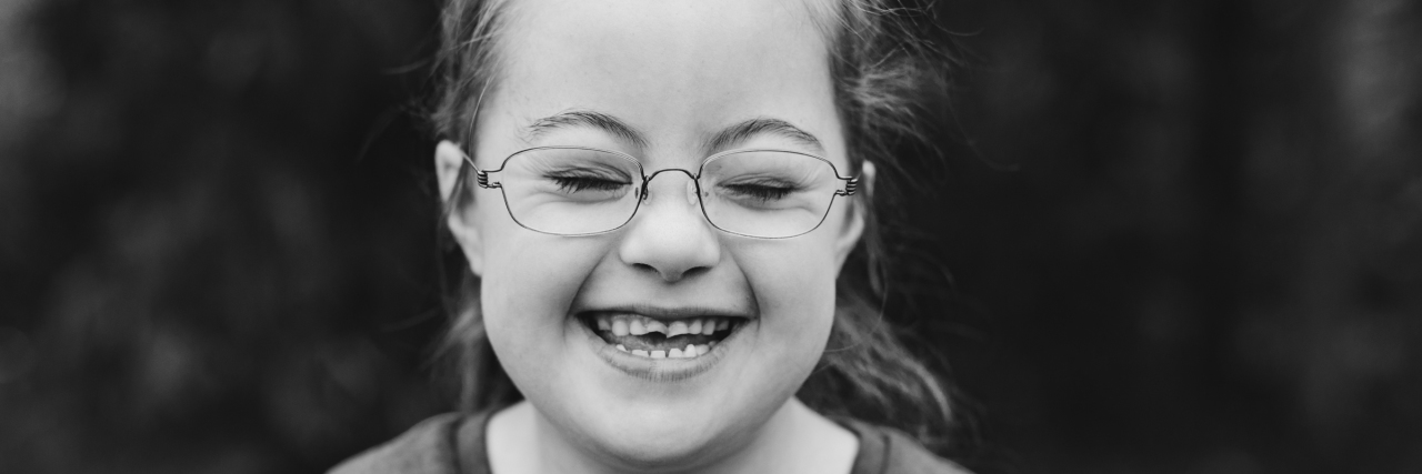 Black and white image of girl with Down syndrome smiling