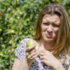 Young woman ate sour unripe apple