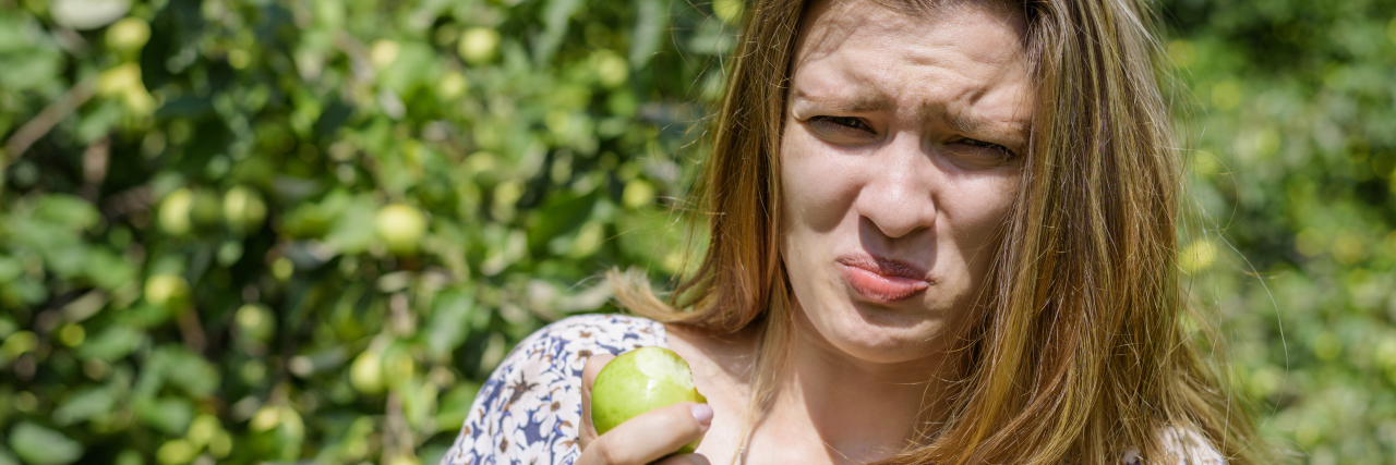 What It's Like to Go Out to Eat When You're a Supertaster Young woman ate sour unripe apple