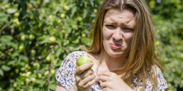What It's Like to Go Out to Eat When You're a Supertaster Young woman ate sour unripe apple