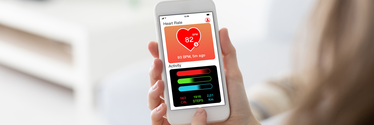How Fitness Apps and Devices Exclude People With Disabilities Female hands holding phone with fitness app on the screen.