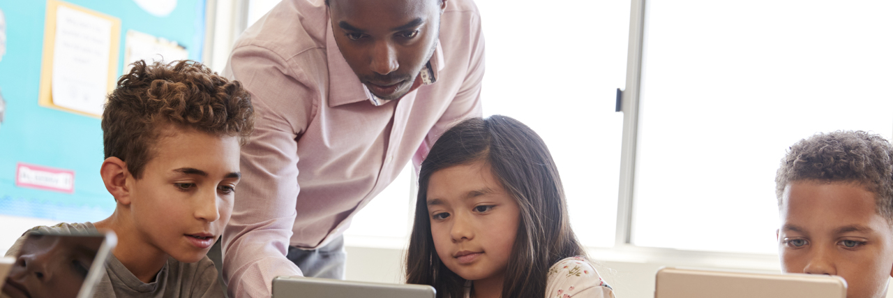 How Schools Can Support Autistic Students Teacher with students using tablets.