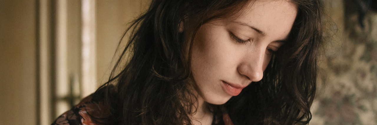 Facing the Reality of a Friend Who Died by Suicide A woman looking down with brown, tousled hair