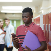 Portrait Of Male High School Student Bullied By Text Message In Corridor
