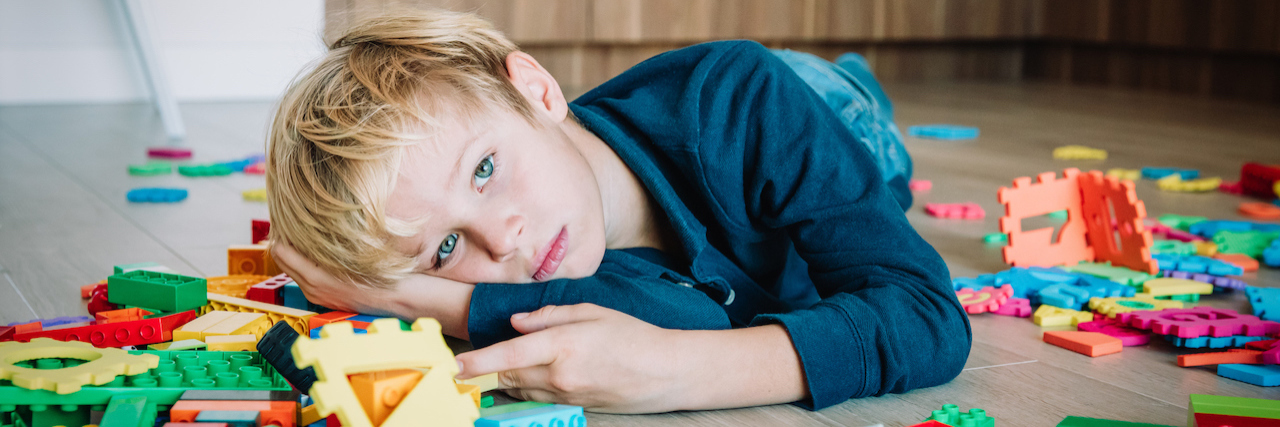 New Study Says 'High-Functioning' Autism Labels Are Harmful sad child, stress and depression, exhaustion with toys scattered around
