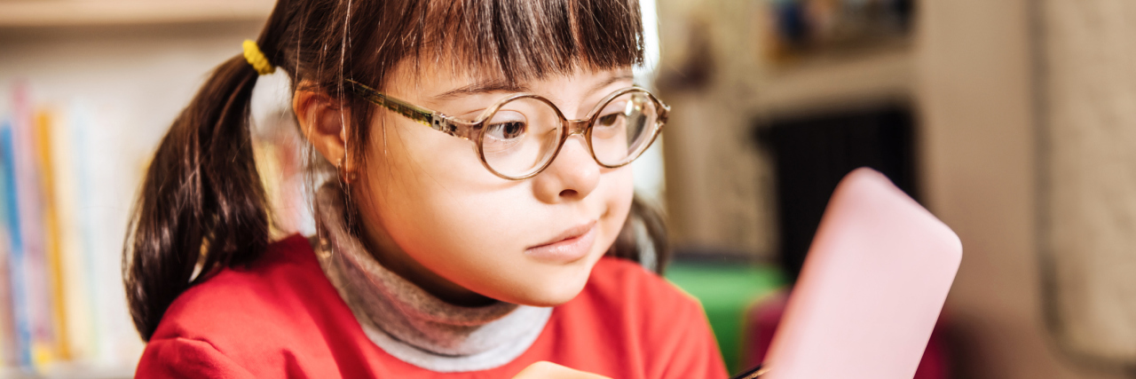 Girl with Down syndrome at school using a tablet with a stylus