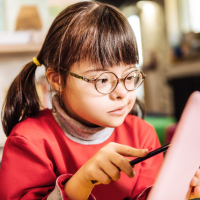Girl with Down syndrome at school using a tablet with a stylus