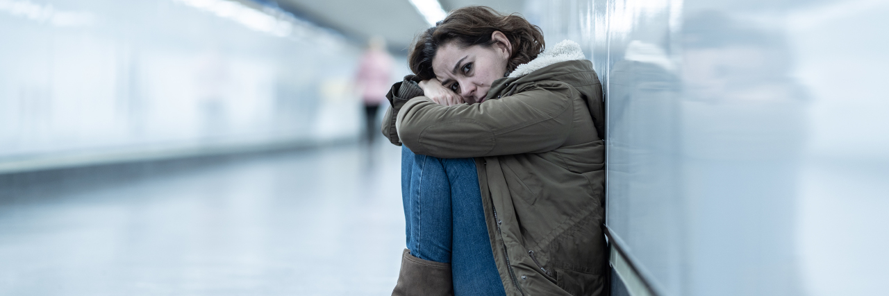 a woman sitting alone on the floor of a subway