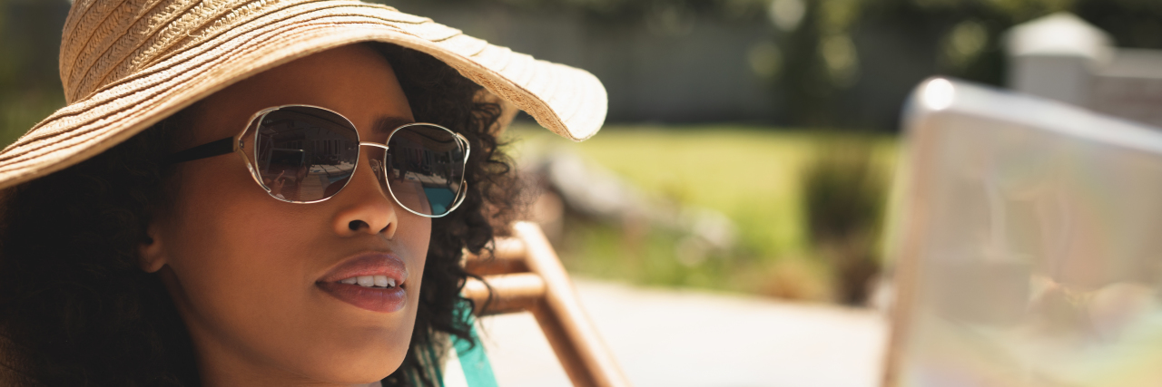 Surviving Summer When You're Sensitive to the Sun African American woman with hat and sunglasses on a sunny day